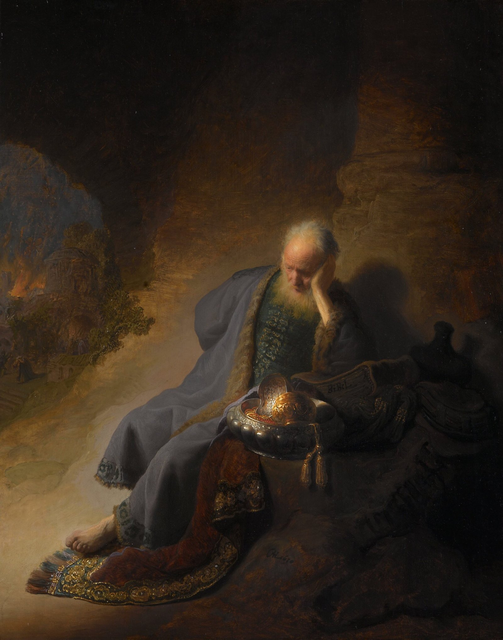 Jérémie, la tête appuyée sur la main, médite dans l’ombre tandis que Jérusalem brûle à l’arrière-plan, dans un tableau de Rembrandt de 1630.