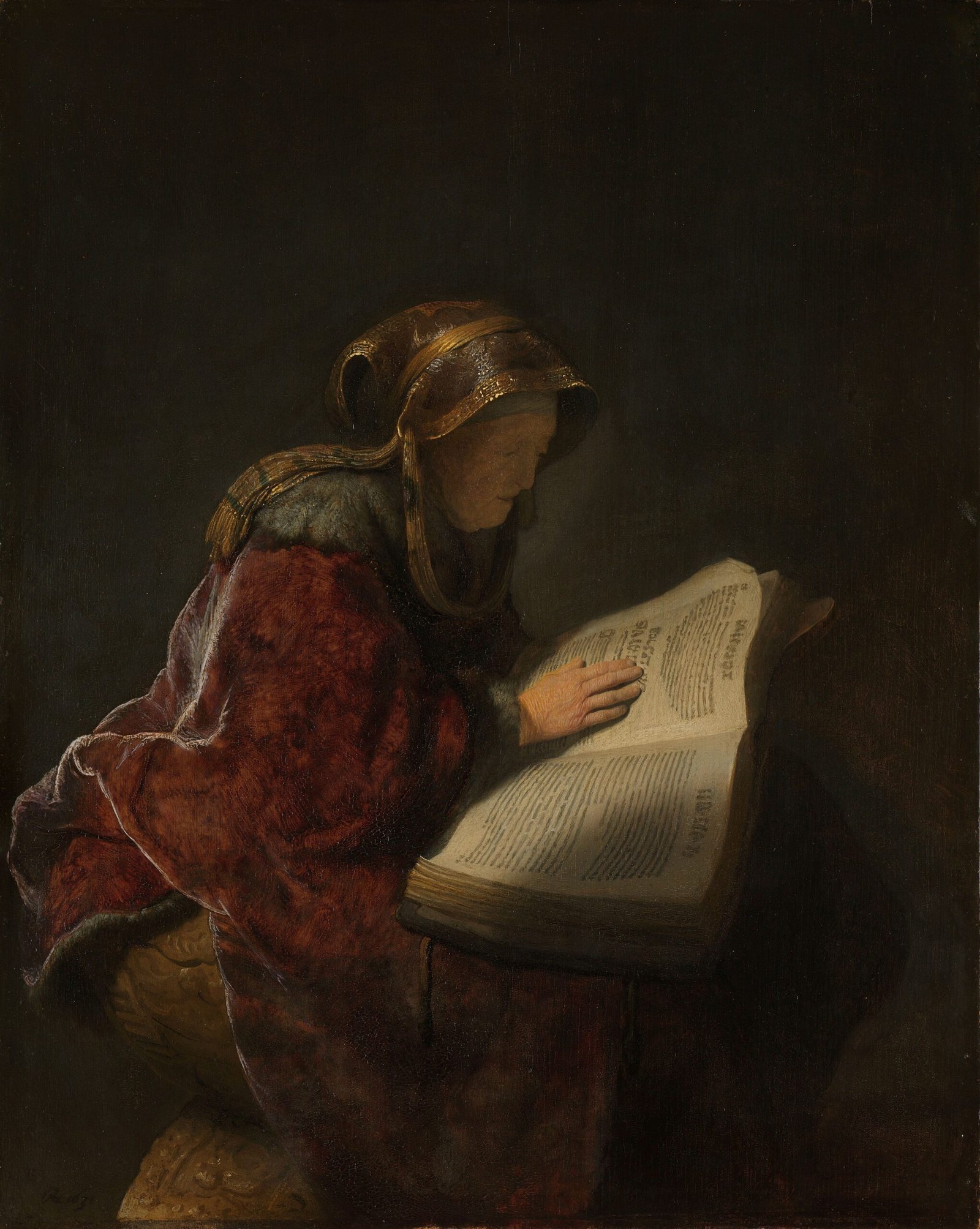 Une femme âgée en manteau rouge lit un grand livre ouvert, dont les pages et sa main sont éclairées dans le clair-obscur, peinture de Rembrandt, 1631.
